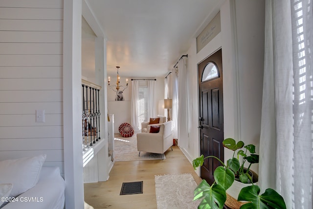 foyer entrance with light wood-type flooring and an inviting chandelier