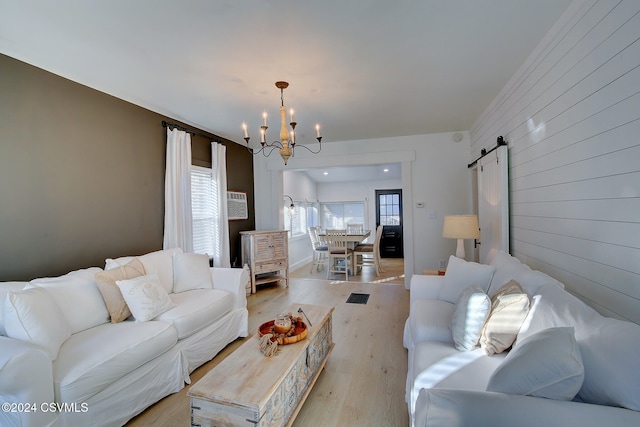 living room featuring light hardwood / wood-style flooring, a barn door, and a chandelier