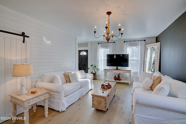 living room featuring a barn door, a chandelier, and light hardwood / wood-style flooring