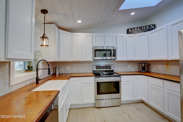 kitchen featuring white cabinets, wooden counters, appliances with stainless steel finishes, and hanging light fixtures