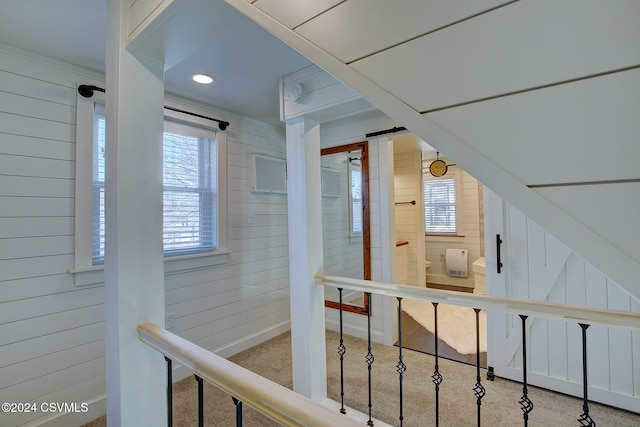 hall with carpet floors and wooden walls