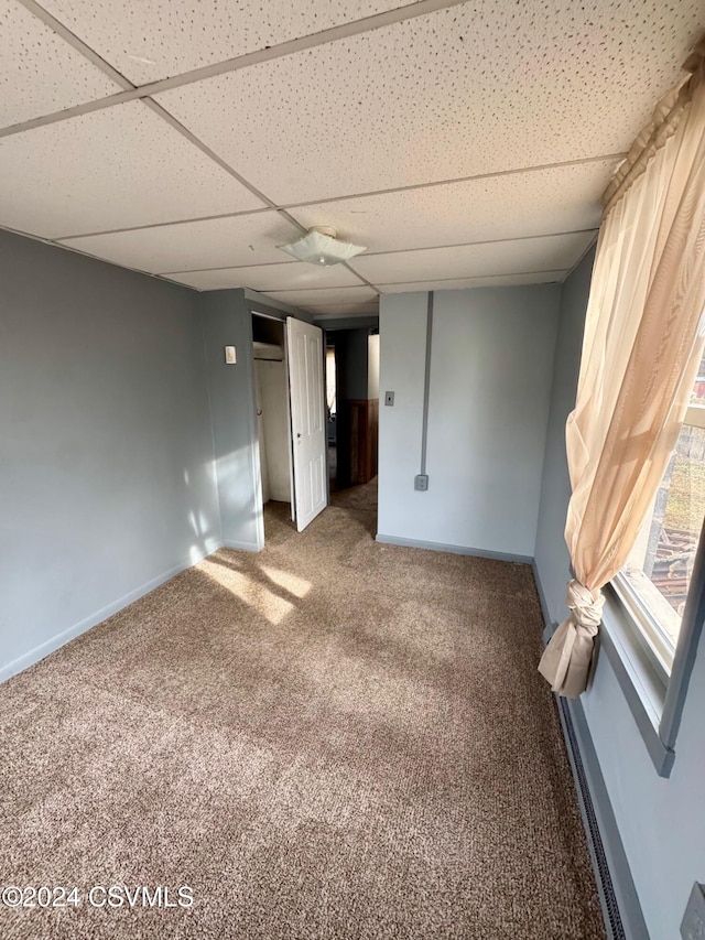 carpeted empty room with a drop ceiling