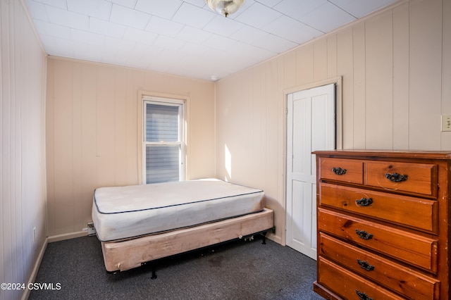 bedroom featuring wood walls and dark colored carpet