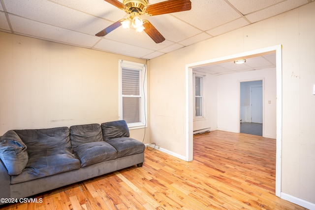 living room with ceiling fan, a drop ceiling, light hardwood / wood-style floors, and a baseboard radiator