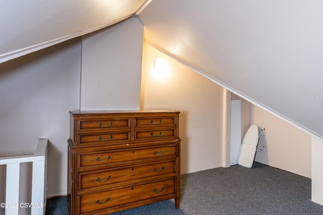 additional living space featuring vaulted ceiling and dark colored carpet