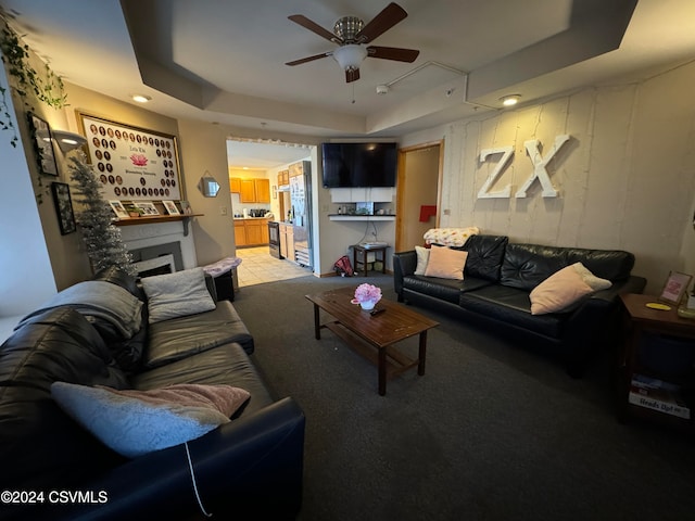 carpeted living room featuring a raised ceiling and ceiling fan