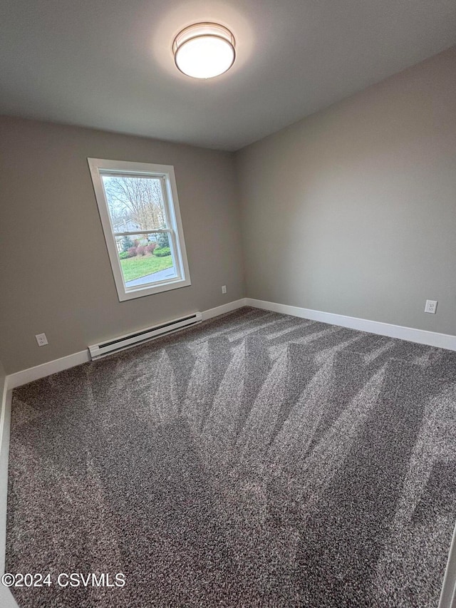 carpeted spare room featuring a baseboard heating unit