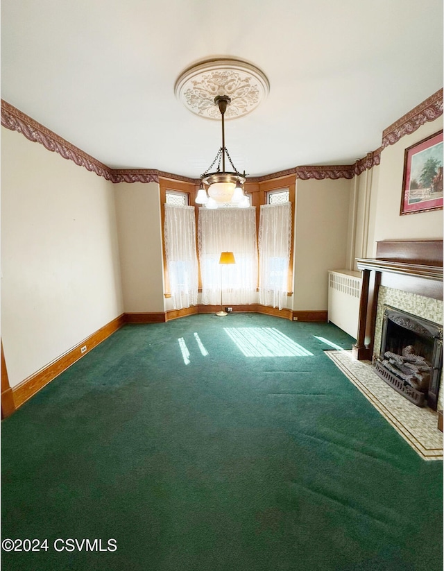 unfurnished living room featuring a fireplace, radiator heating unit, and carpet floors