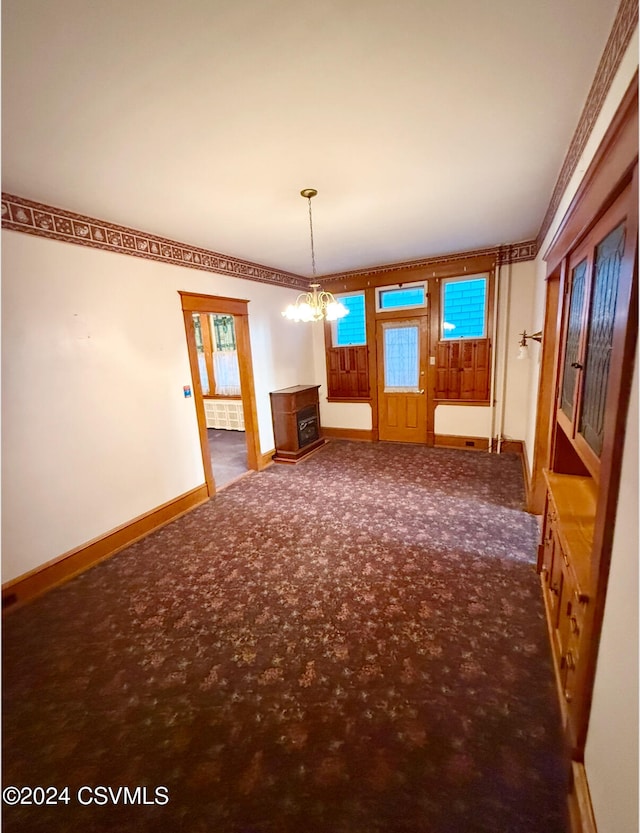 spare room with radiator, a chandelier, and dark carpet