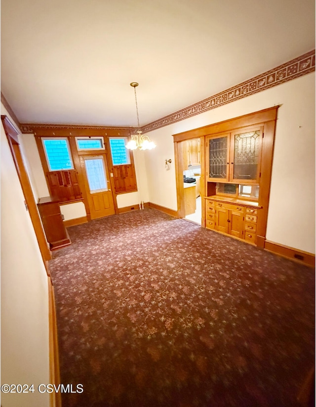 unfurnished living room featuring carpet and an inviting chandelier