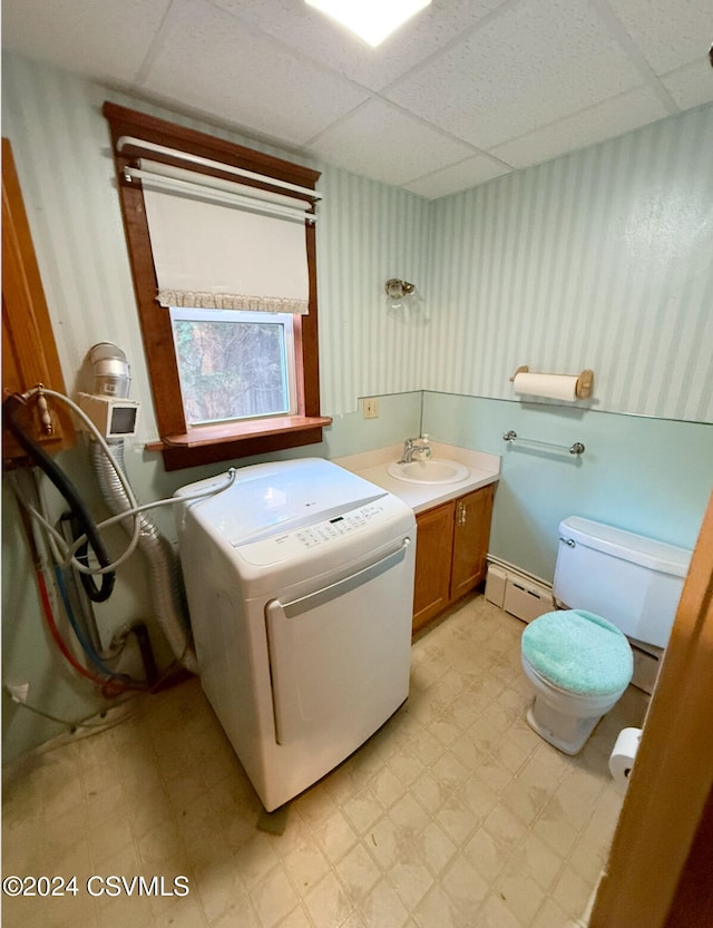 bathroom with a drop ceiling, a baseboard radiator, washer / clothes dryer, toilet, and vanity