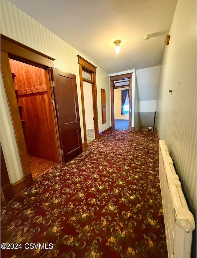 hall featuring dark colored carpet and radiator