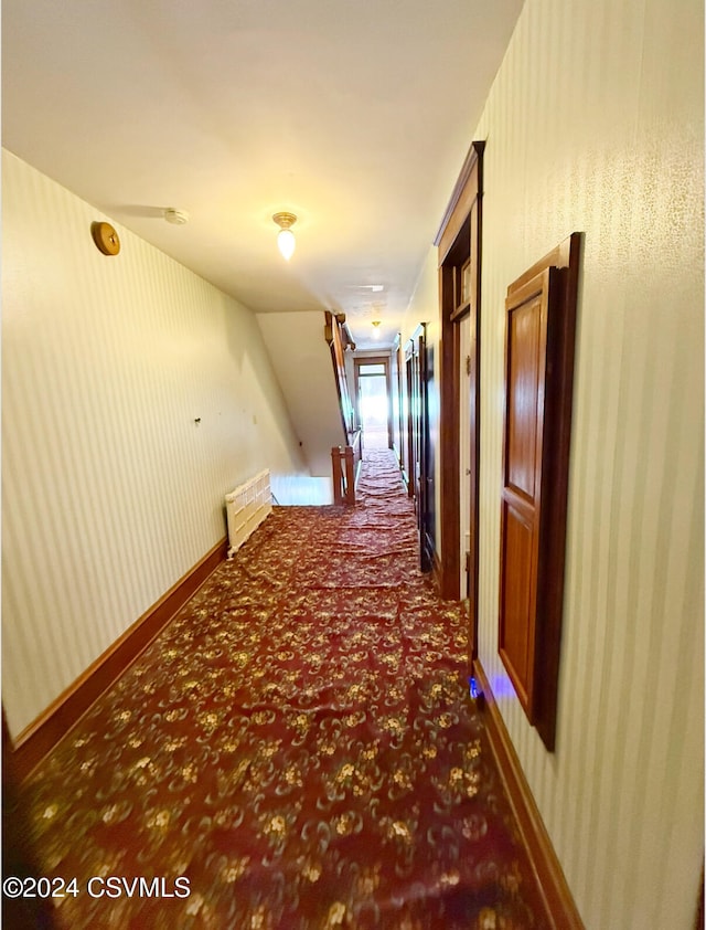 corridor featuring dark colored carpet