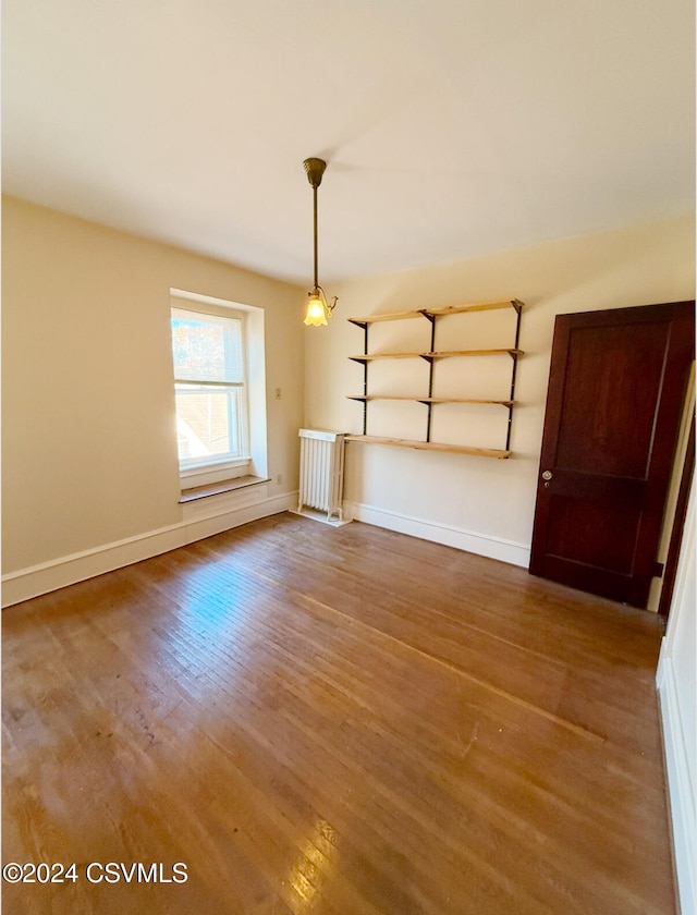 unfurnished dining area featuring hardwood / wood-style floors and radiator