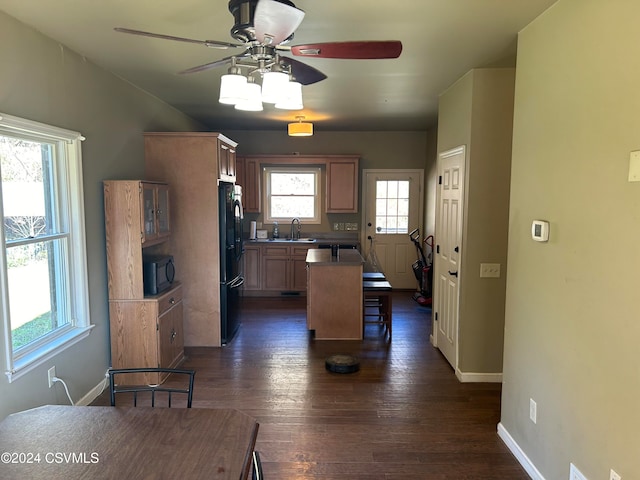 kitchen featuring a center island, black appliances, sink, dark hardwood / wood-style floors, and ceiling fan