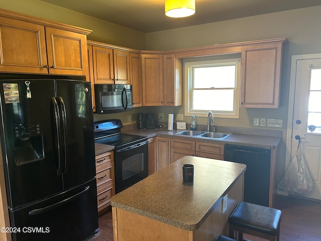 kitchen featuring a kitchen bar, dark hardwood / wood-style flooring, sink, black appliances, and a kitchen island