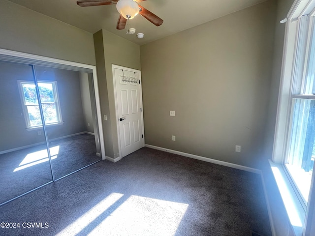 unfurnished bedroom with dark colored carpet, ceiling fan, and a closet