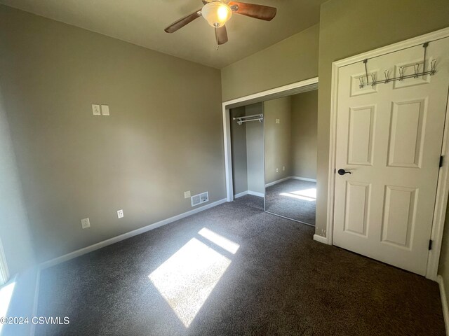 unfurnished bedroom with ceiling fan, a closet, and dark colored carpet