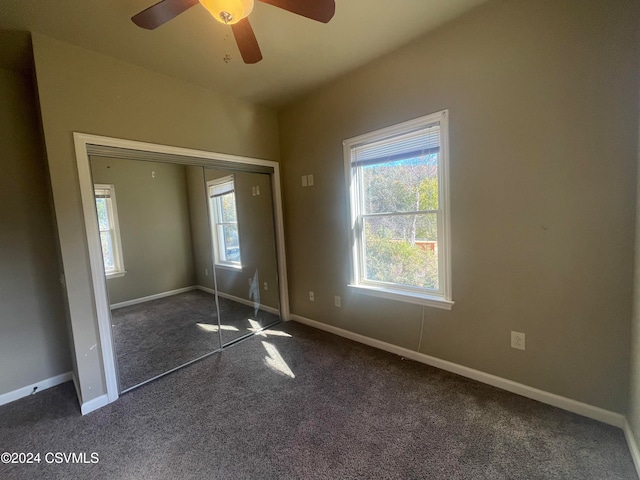 unfurnished bedroom featuring ceiling fan, dark carpet, and a closet