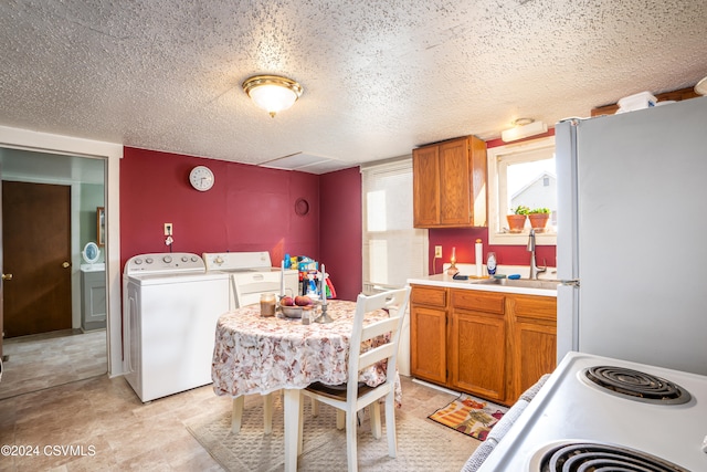 kitchen with sink, washing machine and dryer, a textured ceiling, white fridge, and range