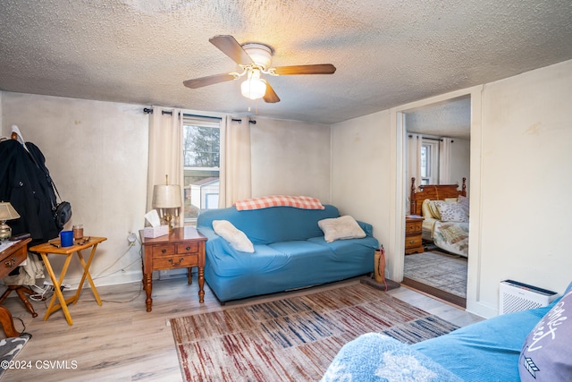 living room featuring a textured ceiling, light hardwood / wood-style flooring, and ceiling fan