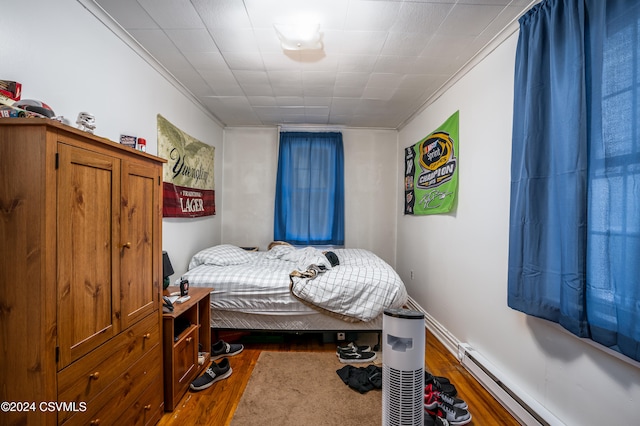 bedroom featuring ornamental molding, a baseboard radiator, and dark wood-type flooring