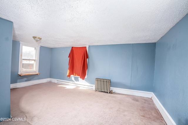 carpeted spare room with baseboard heating, a textured ceiling, and radiator