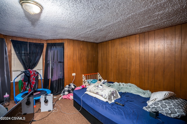 carpeted bedroom featuring a textured ceiling and wood walls