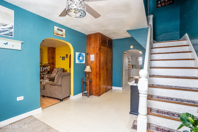 stairs with a textured ceiling and ceiling fan