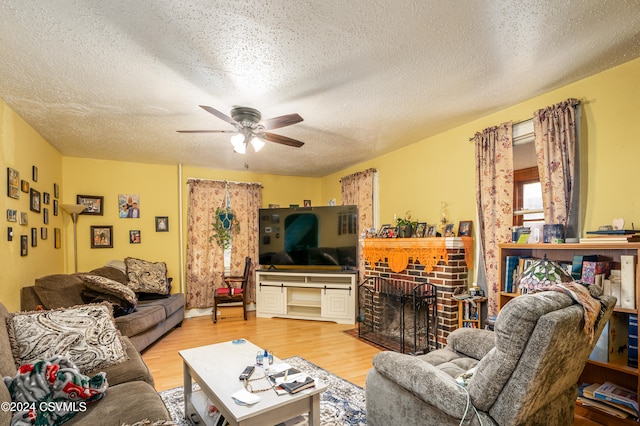 living room with a fireplace, a textured ceiling, hardwood / wood-style flooring, and ceiling fan