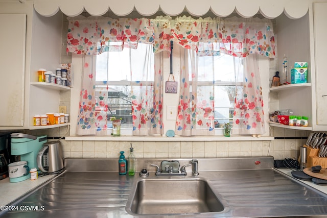 kitchen with tasteful backsplash, stainless steel counters, sink, and a healthy amount of sunlight