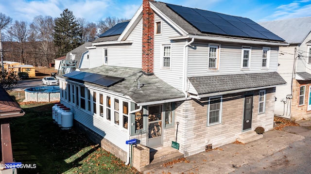 rear view of house with a sunroom and solar panels