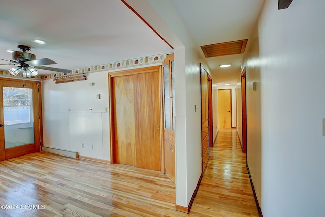 corridor with a baseboard radiator and light hardwood / wood-style flooring