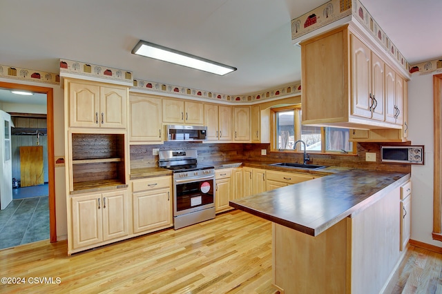 kitchen featuring kitchen peninsula, appliances with stainless steel finishes, backsplash, sink, and light hardwood / wood-style floors