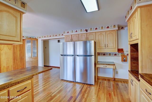 kitchen with stainless steel fridge, light hardwood / wood-style floors, and light brown cabinets