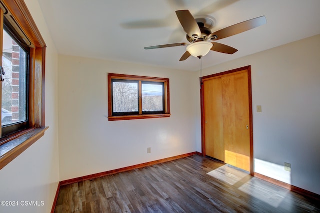 unfurnished bedroom with ceiling fan, a closet, and dark wood-type flooring