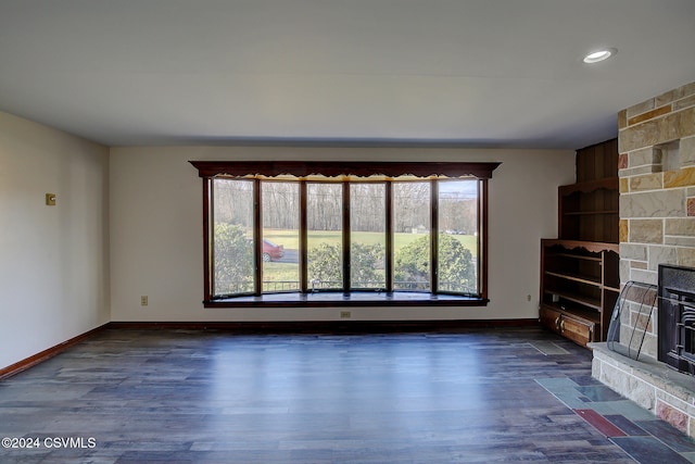 unfurnished living room featuring a stone fireplace and dark hardwood / wood-style floors