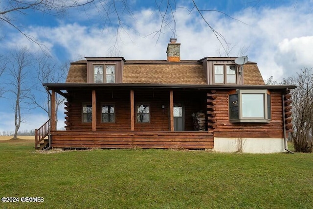 rear view of property with covered porch and a yard