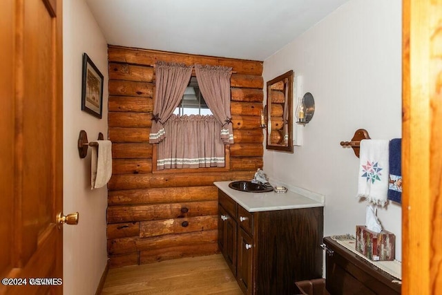 bathroom featuring vanity, hardwood / wood-style flooring, and rustic walls