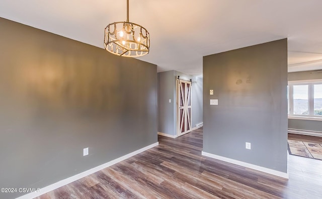 spare room featuring hardwood / wood-style flooring, baseboard heating, and a chandelier