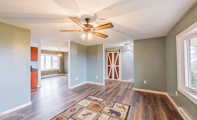 spare room with a barn door, ceiling fan, dark wood-type flooring, and a baseboard heating unit