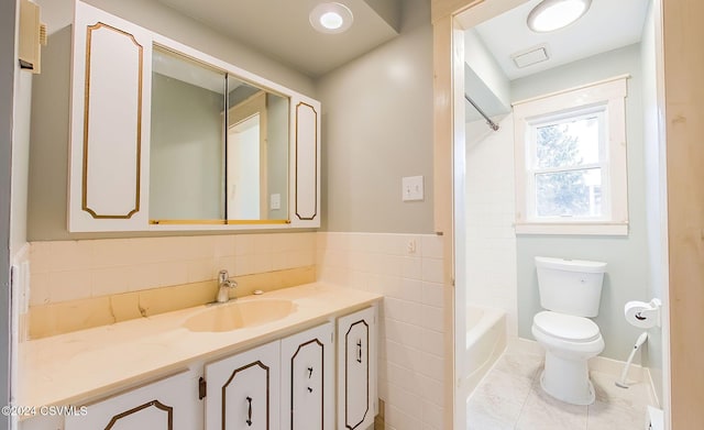 full bathroom featuring tile patterned floors, toilet, shower / washtub combination, vanity, and tile walls