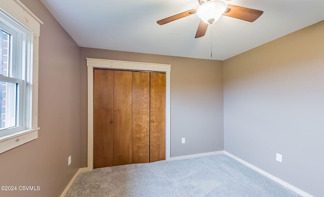 unfurnished bedroom featuring ceiling fan, a closet, carpet floors, and multiple windows