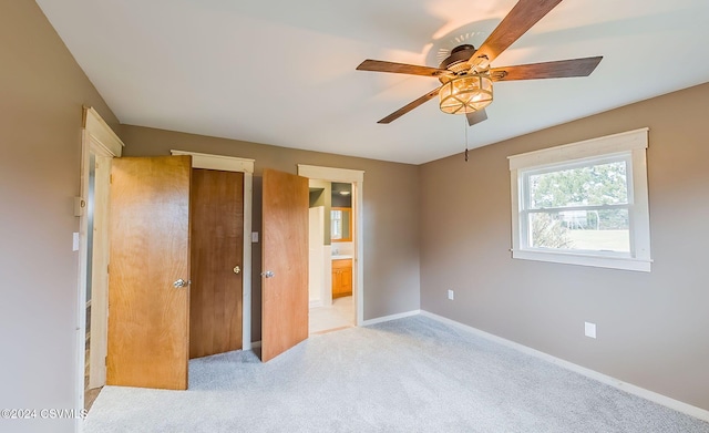 unfurnished bedroom with ceiling fan, light colored carpet, and ensuite bath