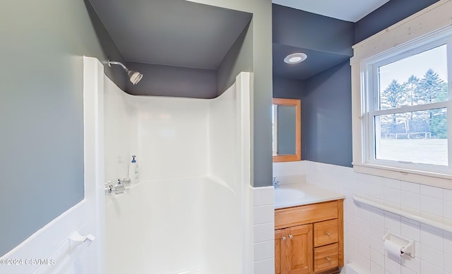 bathroom featuring vanity, shower / bath combination, and tile walls