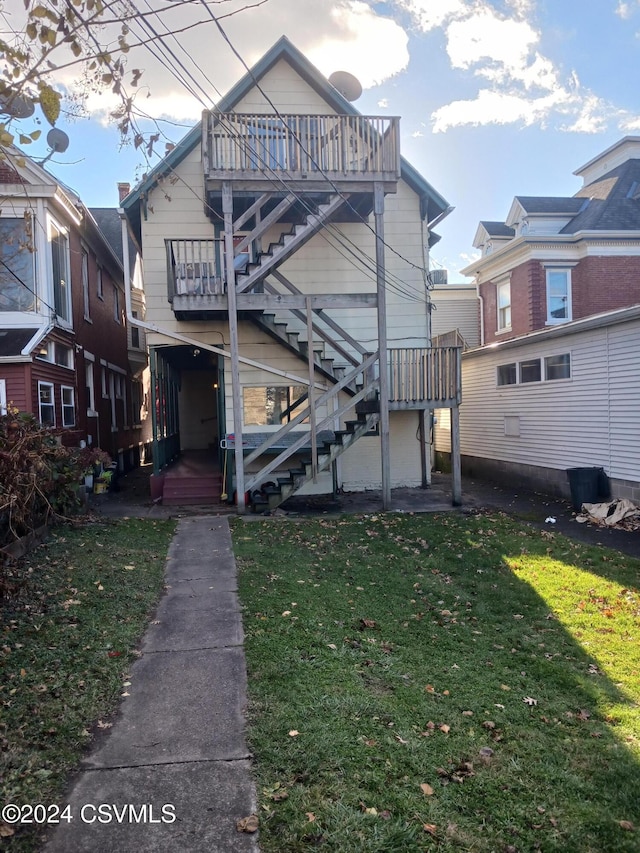 back of house with a balcony and a lawn