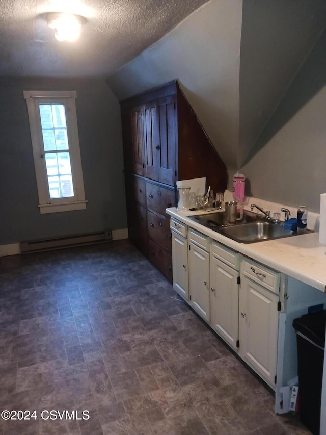 bathroom featuring baseboard heating, lofted ceiling, sink, and a textured ceiling