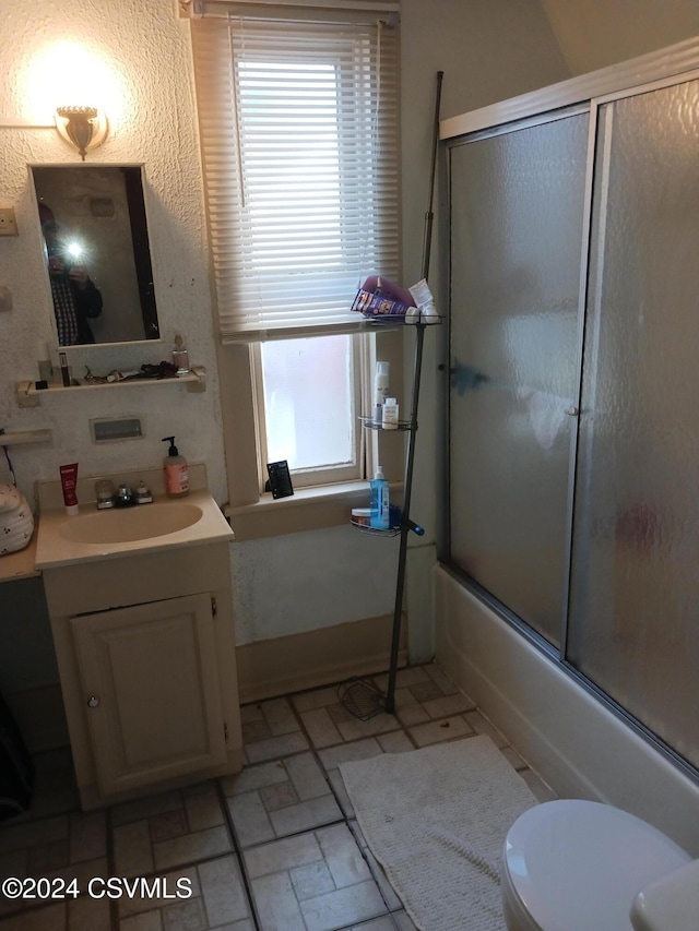 full bathroom featuring toilet, vanity, and combined bath / shower with glass door