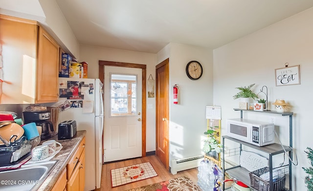 doorway to outside with light hardwood / wood-style floors, sink, and baseboard heating