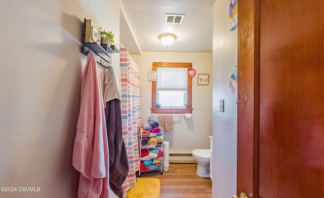 bathroom with hardwood / wood-style floors, toilet, and baseboard heating